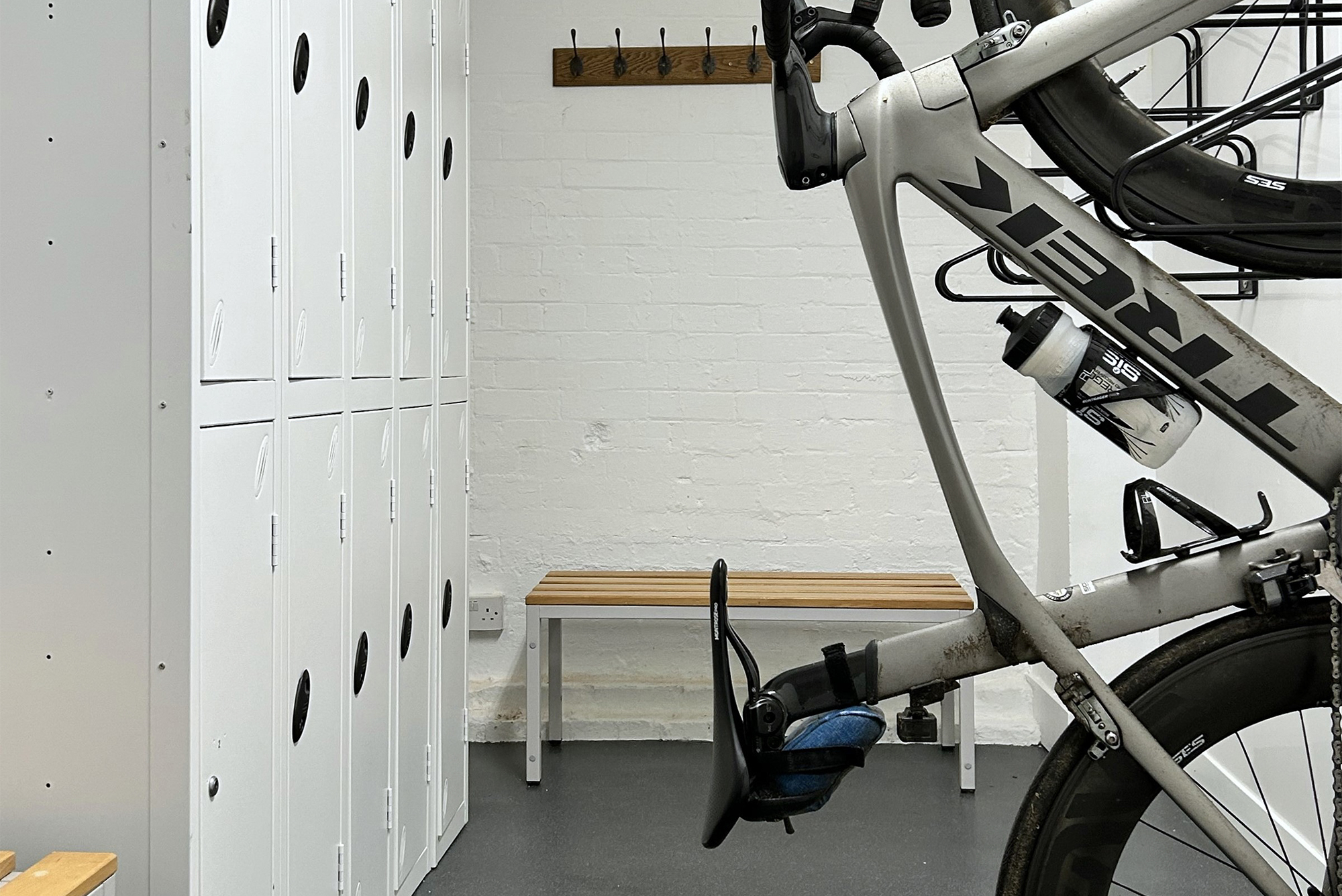 Bicycle store with grey Trek racing bike hanging on wall and white metal lockers.