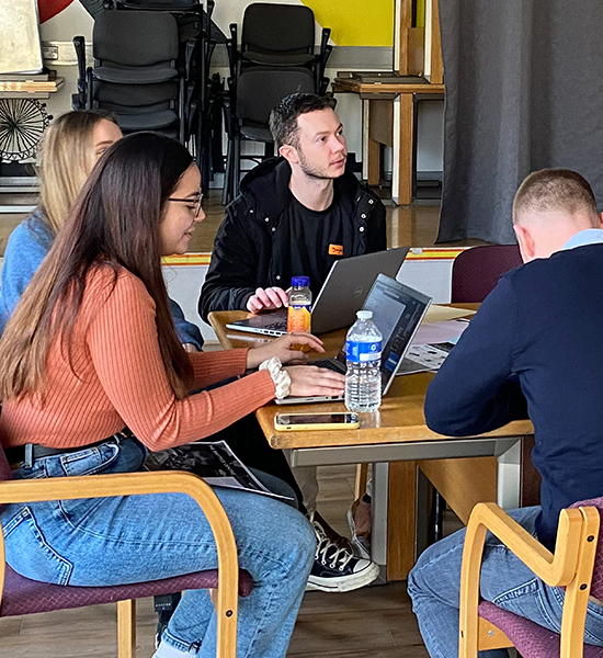 Group of four 1st Formations’ staff members working at a table with laptops during a WONDER Foundation volunteering day at The Baytree Centre in Brixton.